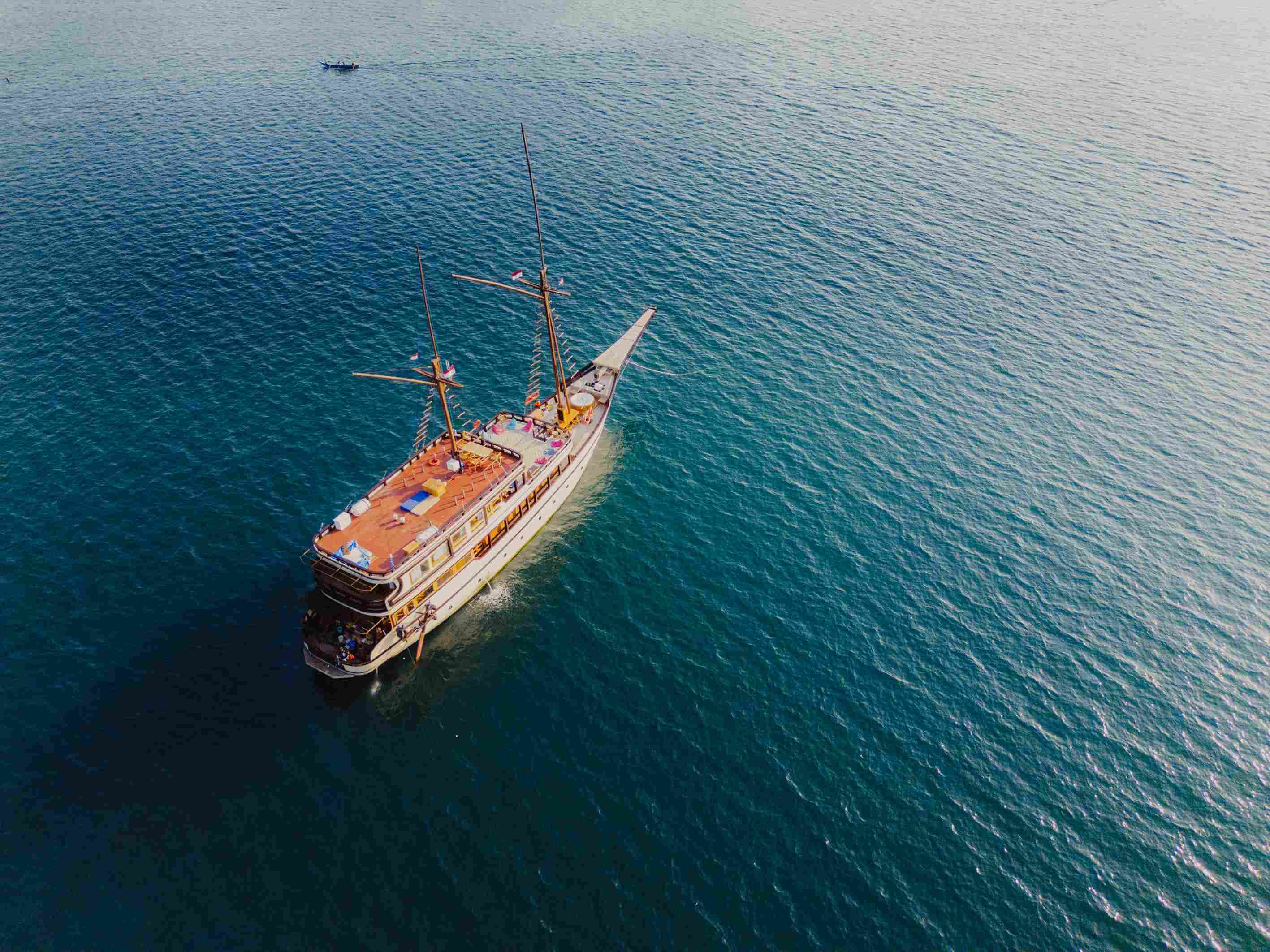 Aerial view of a classic Phinisi boat sailing past rugged islands